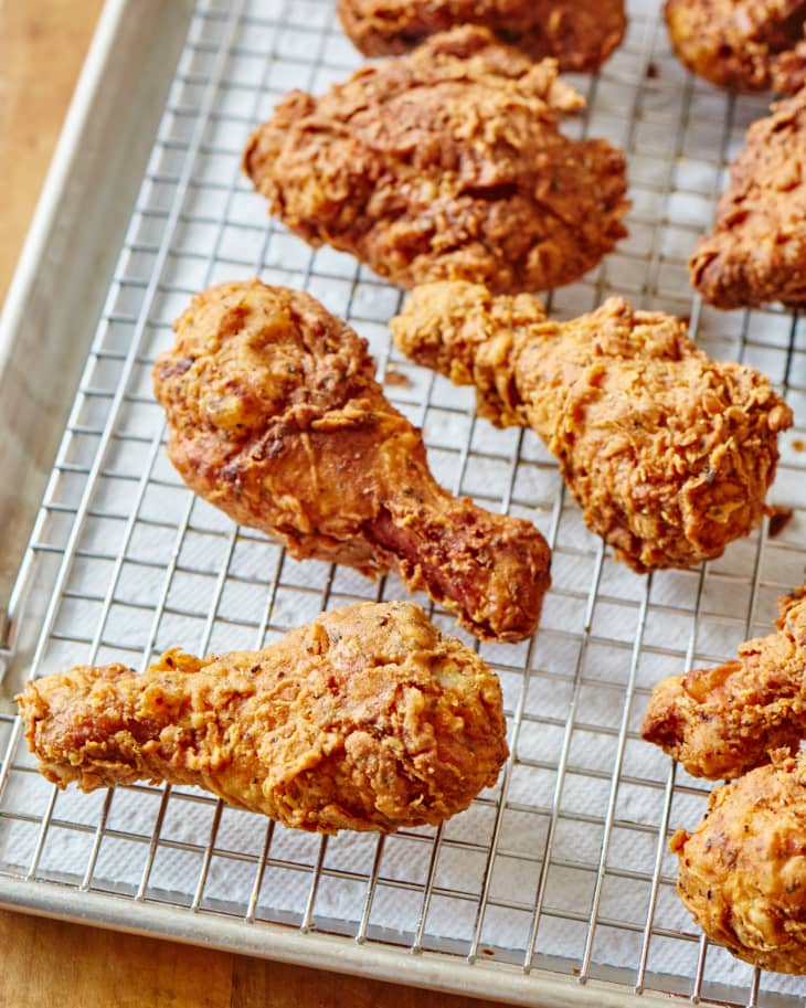 Pieces of fried chicken on a rack over a paper towel-lined sheet pan