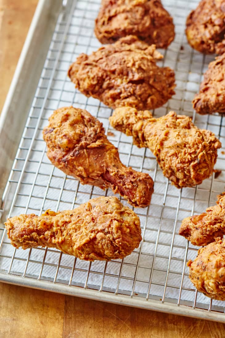Pieces of fried chicken on a rack over a paper towel-lined sheet pan
