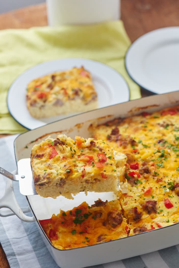 Cheesy hash brown breakfast casserole with sausage and peppers in a baking dish, garnished with parsley.