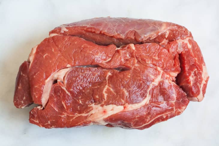 Raw beef chuck roast on a light surface, showcasing marbled texture.