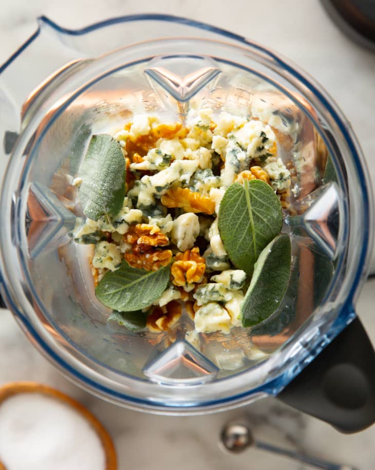 Walnuts, Roquefort cheese, and sage leaves in a blender jar.