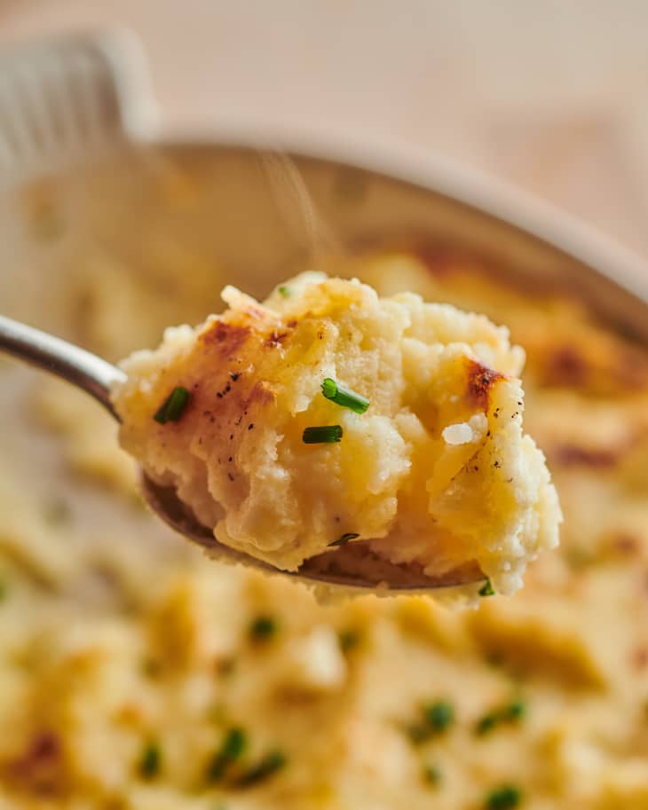 Spoonful of cheesy baked mashed potatoes topped with chives.
