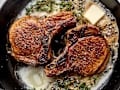 Pork chops in a skillet with butter and thyme