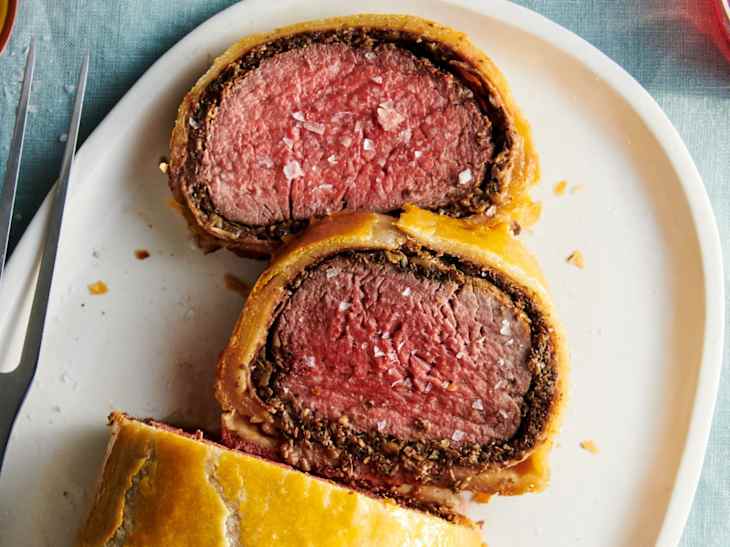Overhead shot of beef Wellington on a platter, two slices cut crosswise and laid flat to show interior