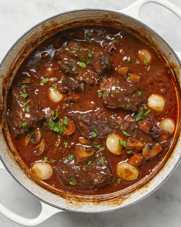 Overhead shot of beef bourguignon in a white pot.