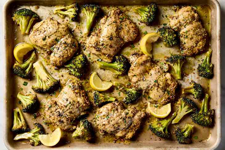 overhead shot of zaatar roasted chicken and broccoli on a sheet pan.