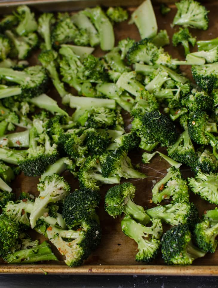 Roasted broccoli florets on a baking sheet with garlic and red pepper flakes.
