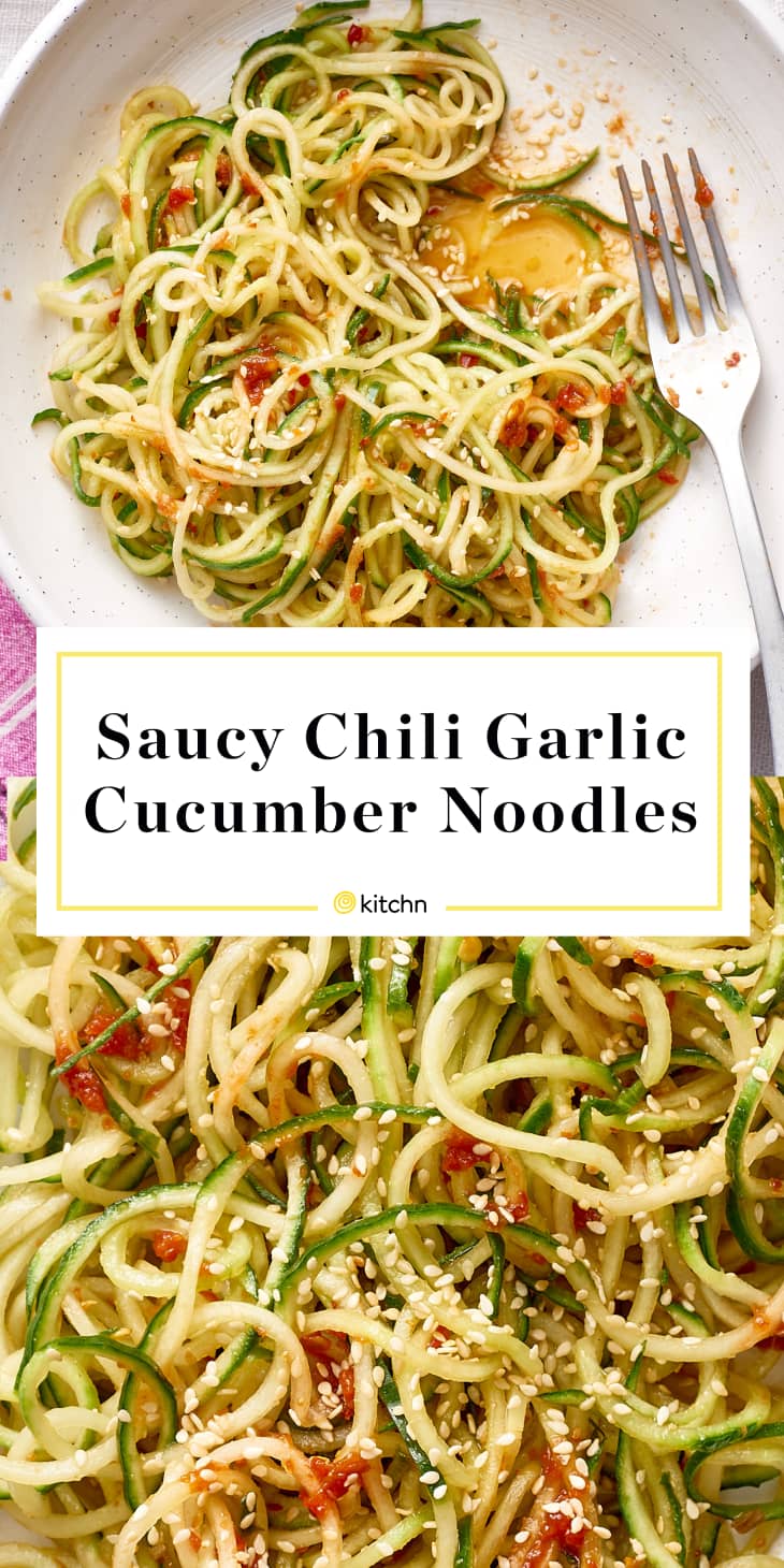Cucumber noodles with chili-garlic sauce, sesame seeds, and a fork on a white plate.