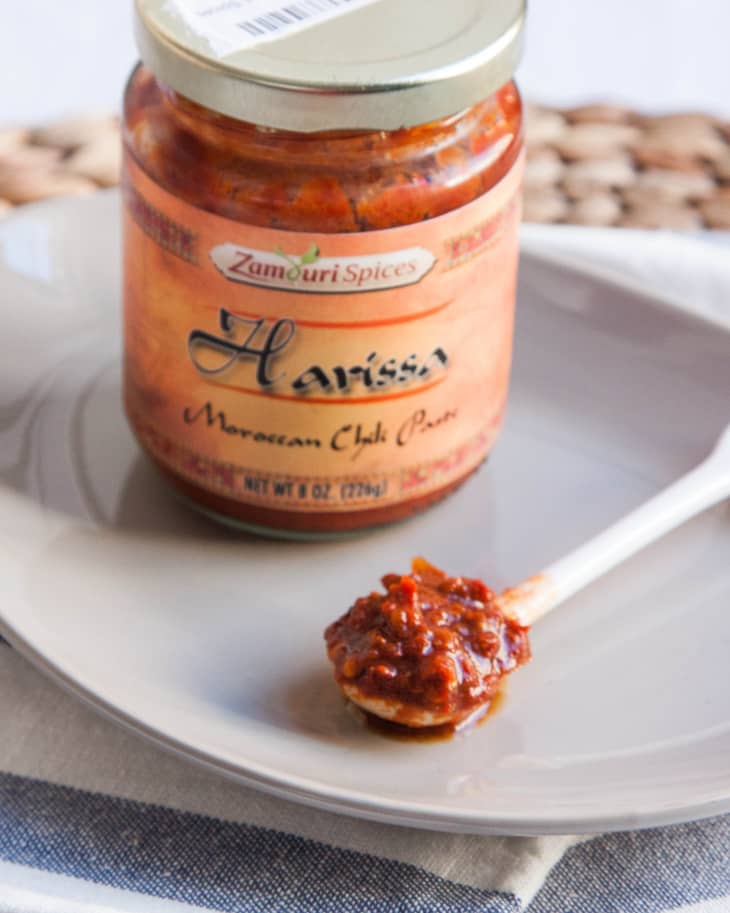 Jar of Zamouri Spices Harissa Moroccan Chili Paste on a plate with a spoonful of paste.