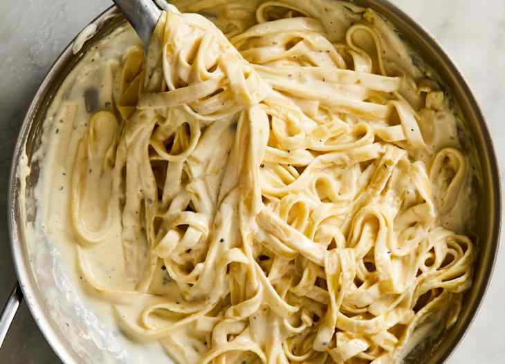 fettuccini Alfredo in pot being picked up by tongs