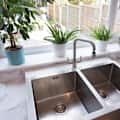 kitchen interior with a modern stainless steel twin sinks by a window with a view into the garden