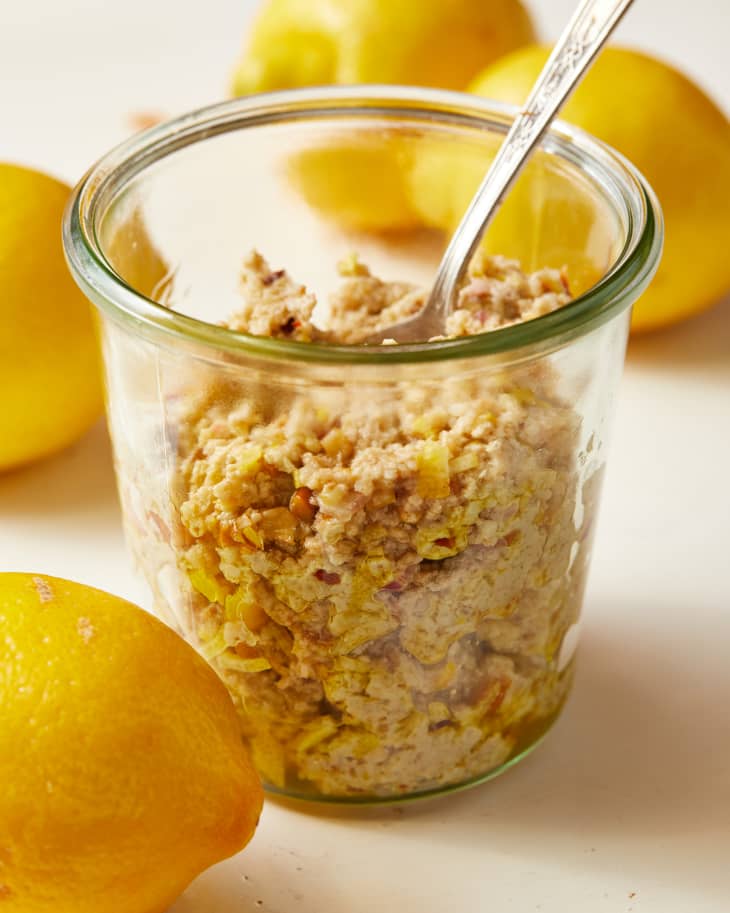 Jar of lemon pesto with walnuts and pecorino, surrounded by fresh lemons.