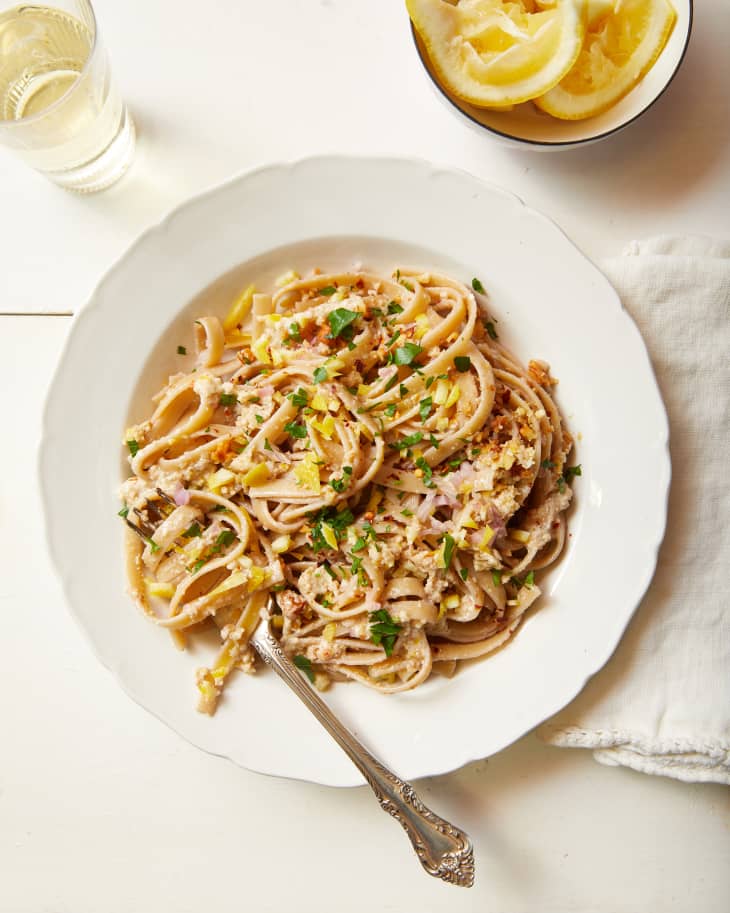 overhead photo of pasta with lemon pesto in white shallow bowl on white surface