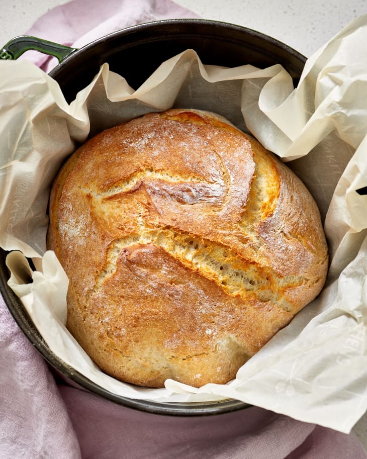 Baked loaf of bread in parchment paper and dutch oven