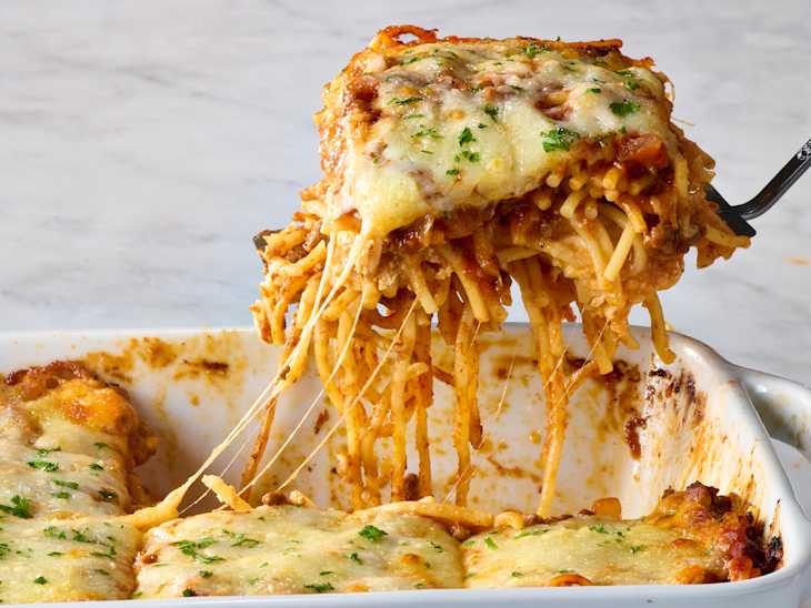 head on shot of baked spaghetti in a baking dish, with a piece taken out of the dish