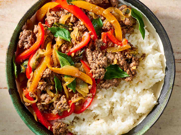 Bowl of white rice topped with seasoned ground beef, sautéed bell peppers, and fresh basil.