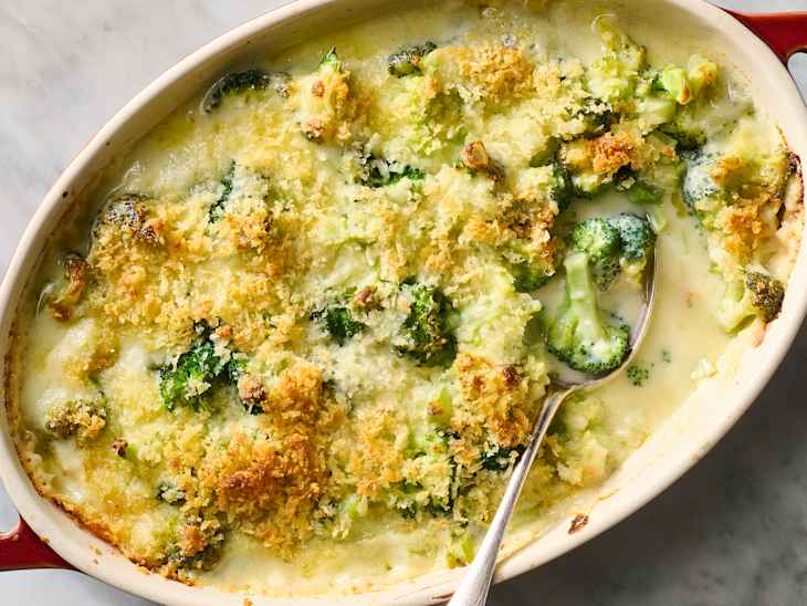 Creamy broccoli casserole topped with golden breadcrumbs in a baking dish, with a serving spoon.