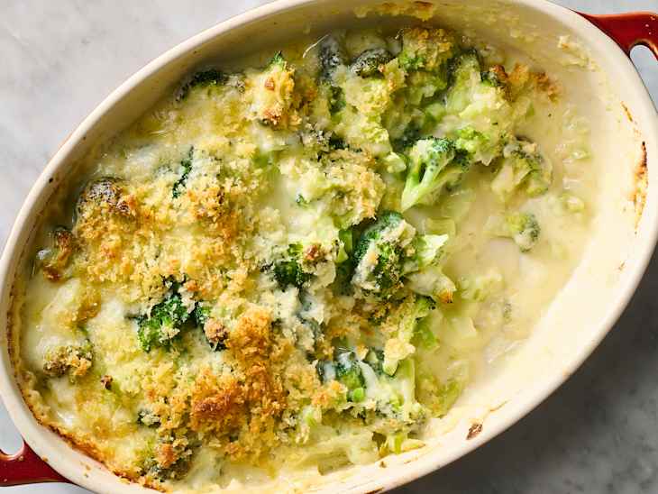 Creamy broccoli casserole topped with golden breadcrumbs in a baking dish, with a serving spoon.