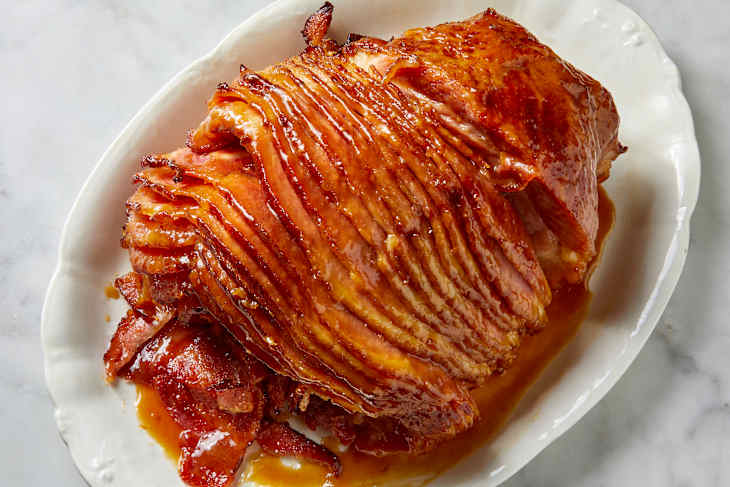 Overhead shot of a glazed spiral cut ham on a white platter.