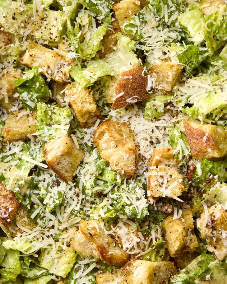 overhead shot of caesar salad in a large salad bowl, topped with parmesan cheese
