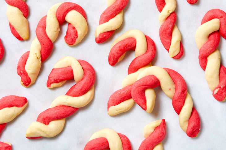 Overhead shot of baked candy cane cookies on white parchment paper.