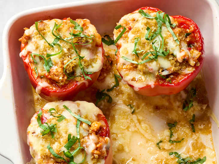 overhead shot of three stuffed peppers in a white baking dish, topped with herbs