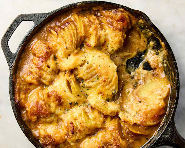 Cheesy French onion potato bake in a cast iron skillet, some removed from pan