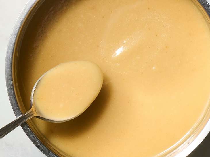 chicken gravy in a stainless steel pot being mixed by a spoon