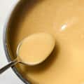 chicken gravy in a stainless steel pot being mixed by a spoon