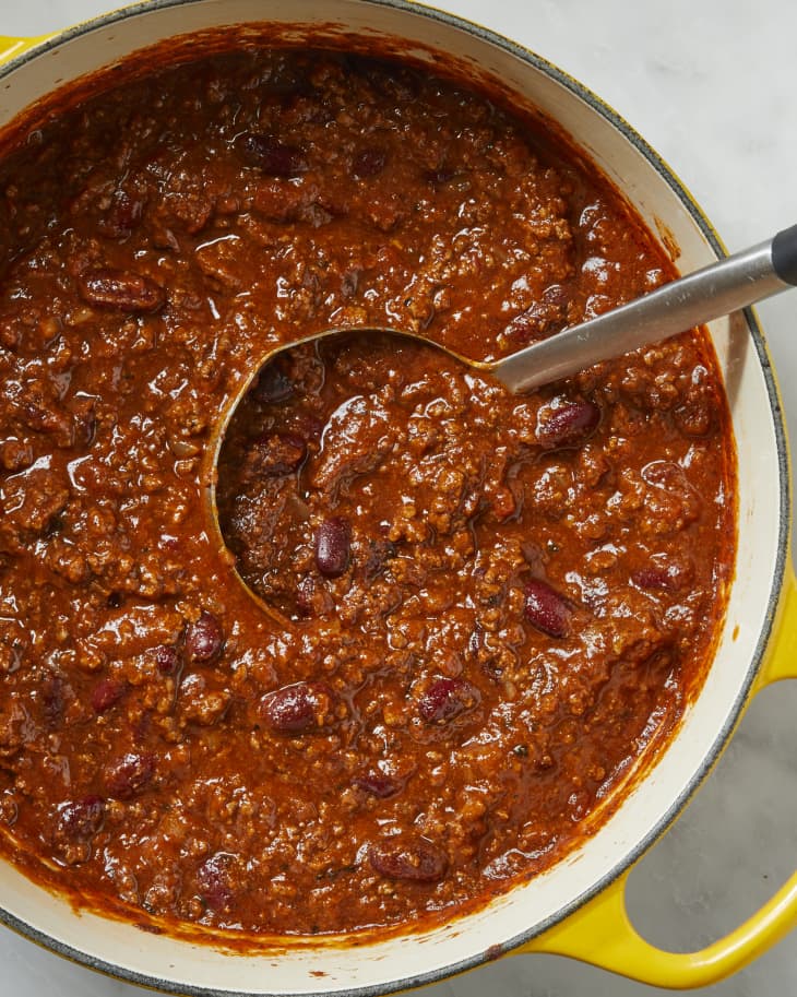 Overhead shot of chili in a yellow pot with a metal ladle resting in it.