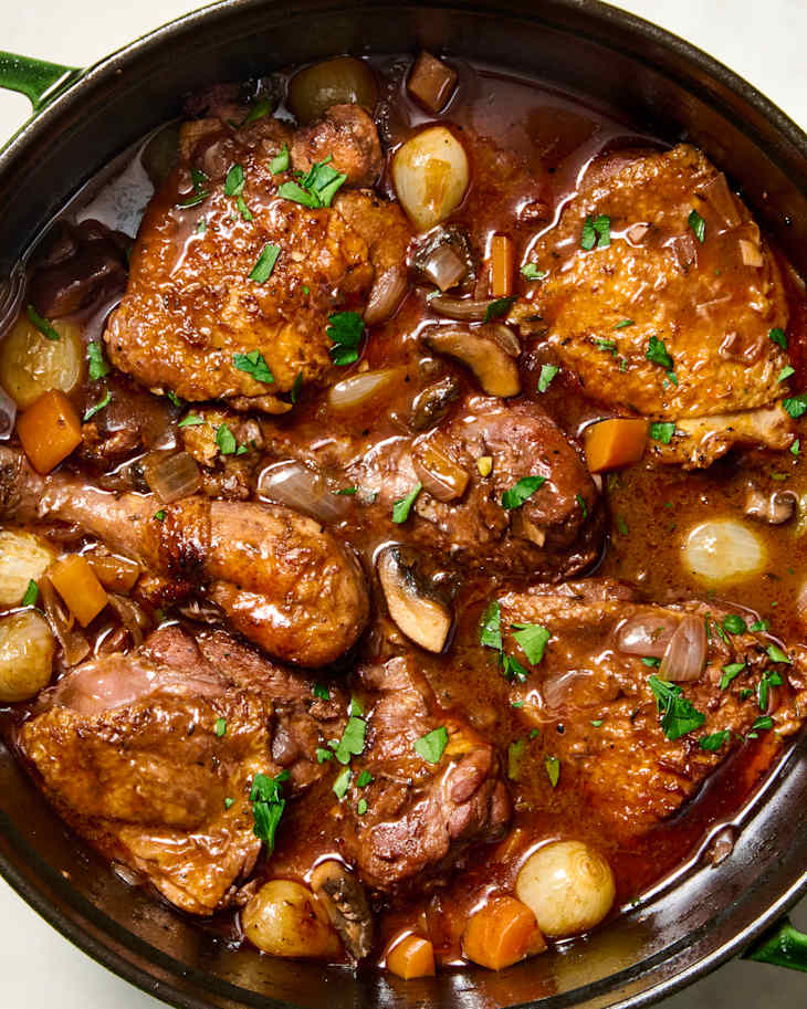 An overhead view of a green dutch oven with coq au vin