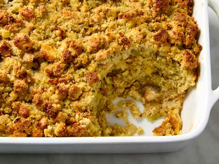 overhead shot of  cornbread dressing in a white rectangular dish, with a scoop taken out of it