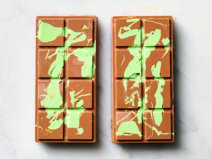 Two chocolate bars with green swirls on a light surface, showcasing a unique dessert presentation.