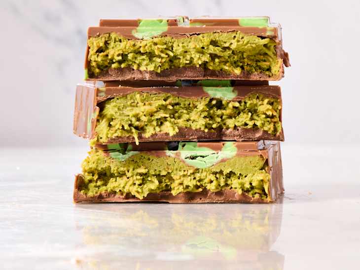 Three stacked chocolate bars with a green, textured filling, showcasing a layered dessert.