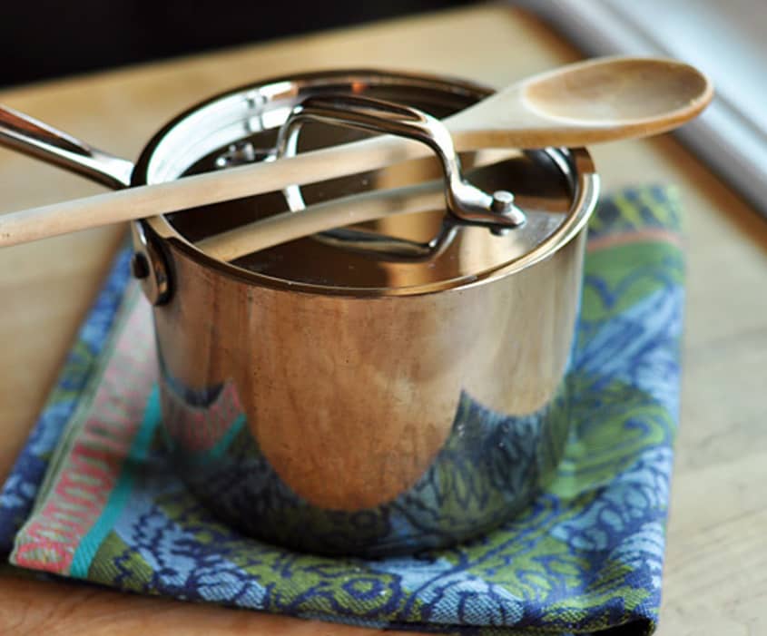 A stainless steel pot with a wooden spoon on a patterned cloth, ready for cooking couscous.