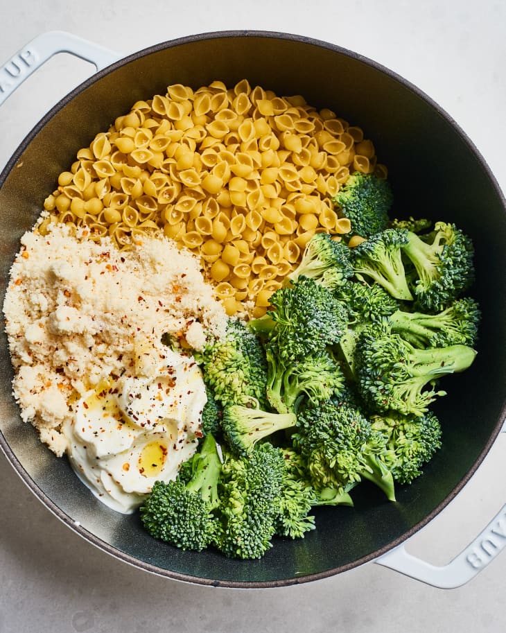Pasta shells, broccoli, ricotta, and breadcrumbs in a pot, ready for cooking.