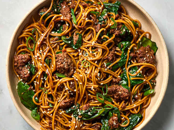 overhead shot of sesame noodles with ground beef and spinach in a bowl