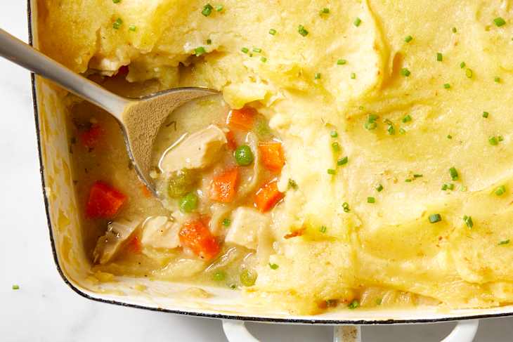 Close up view of the corner of the french chicken casserole with a scoop taken out of it.