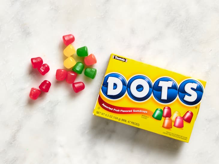 Colorful Dots gumdrops in red, yellow, green, and orange scattered around a yellow box labeled "DOTS."