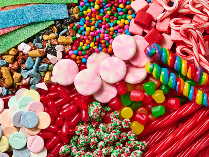 A colorful assortment of candies including gummy bears, peppermint disks, candy canes, and chocolate rocks.