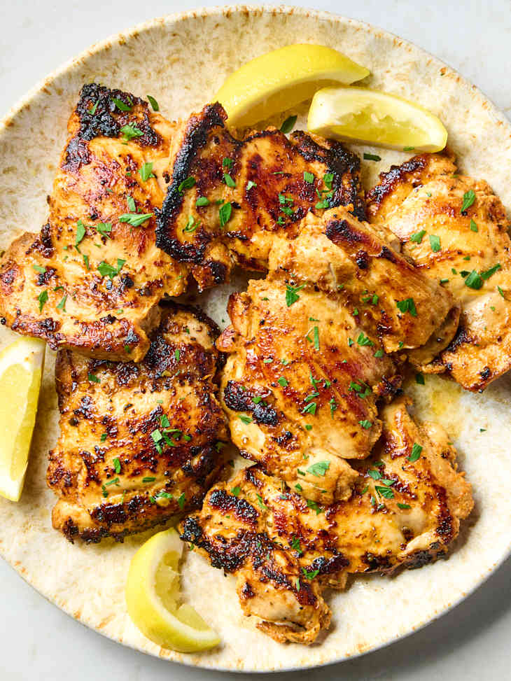 overhead shot of greek chicken on a plate with lemon wedges
