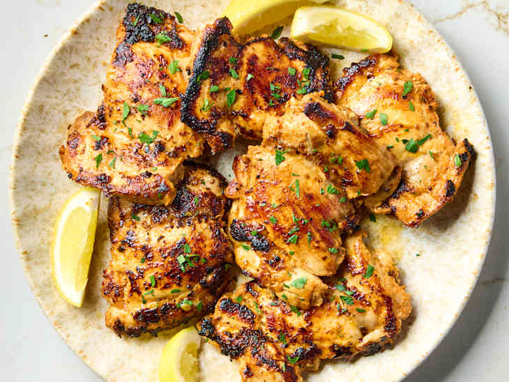 overhead shot of greek chicken on a plate with lemon wedges