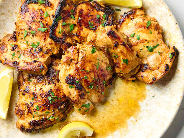 overhead shot of greek chicken on a plate with lemon wedges