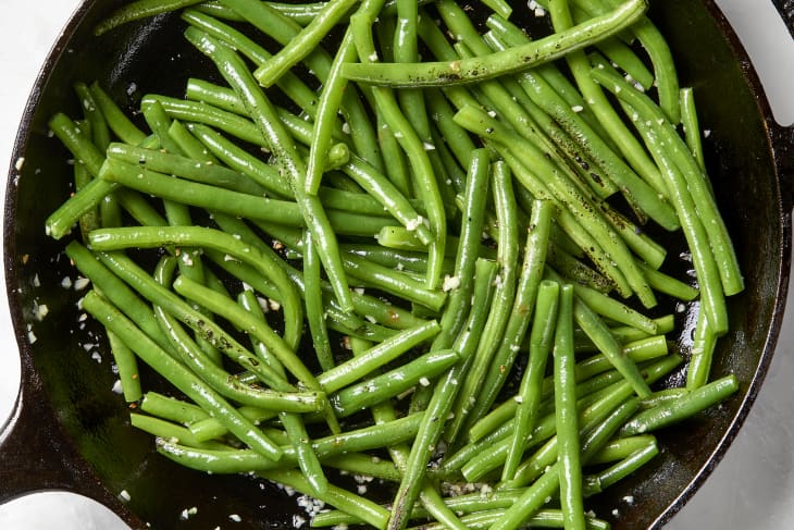 overhead shot of green beans and garlic in a cast iron pan