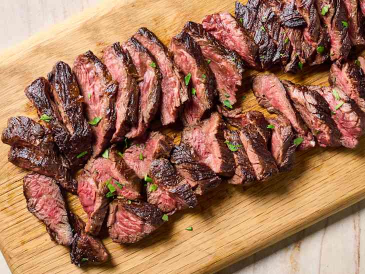 overhead shot of hanger steak on a wooden cutting board, sliced