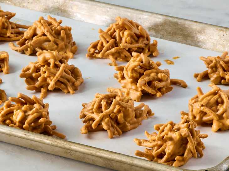 Clusters of crunchy snacks coated in a creamy peanut butter mixture, arranged on parchment paper.