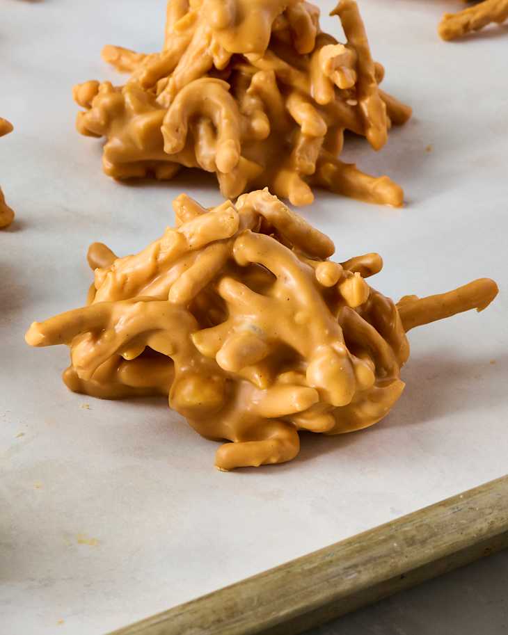 Clusters of crunchy snacks coated in a creamy orange caramel on parchment paper.