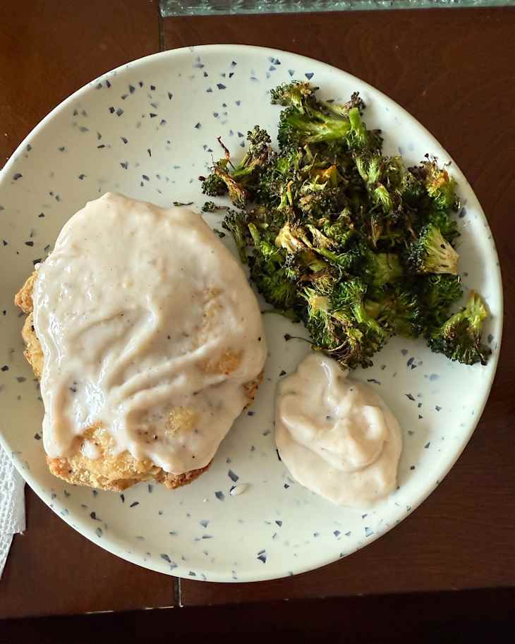 Plated dinner with chicken fried chicken smothered with gravy.