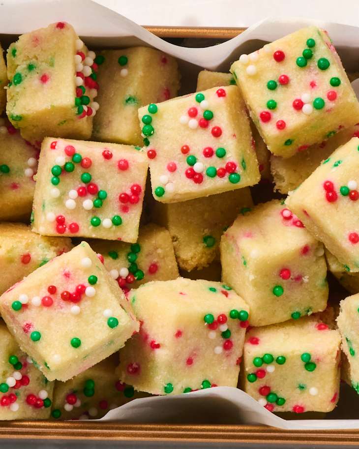 Colorful holiday shortbread bites with red, green, and white sprinkles arranged in a tray.