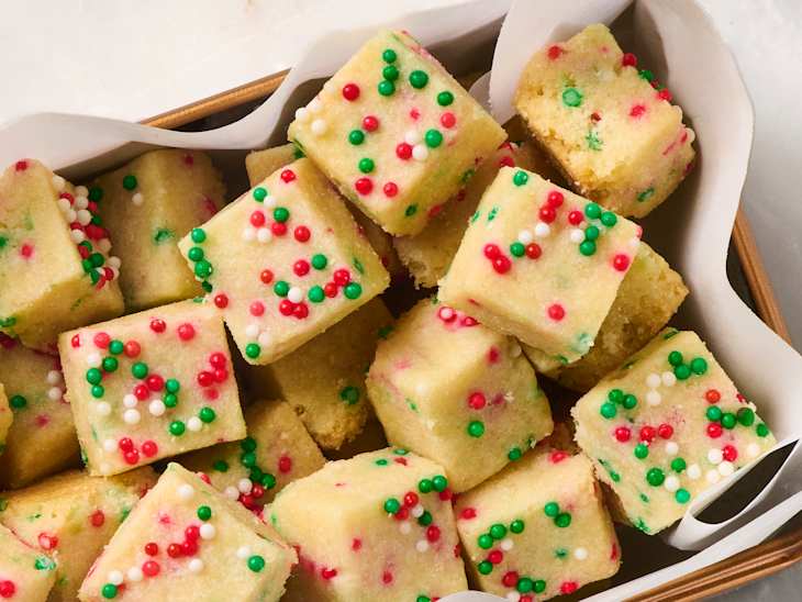 Colorful shortbread bites topped with red, green, and white sprinkles in a basket.